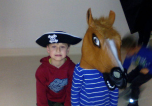 Dwaj chłopcy w czapce pirata oraz masce konia pozują do zdjęcia.